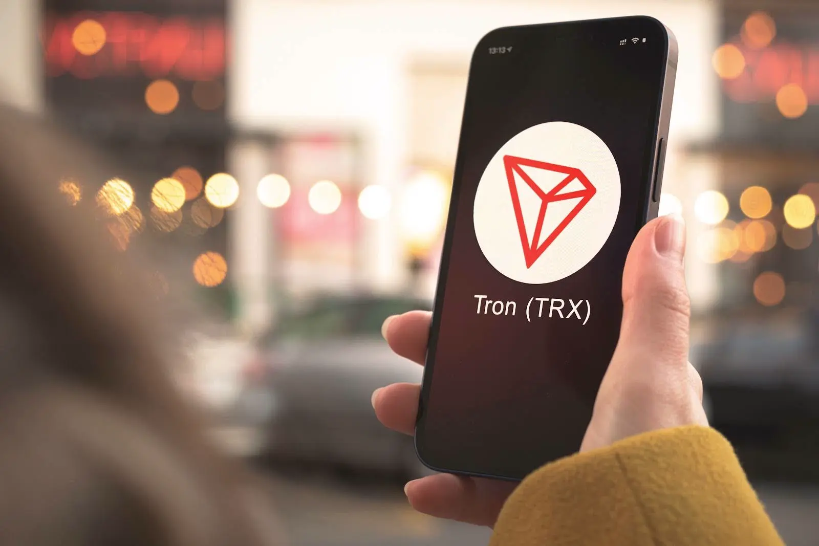 Une main tenant un smartphone avec le symbole du jeton Tron