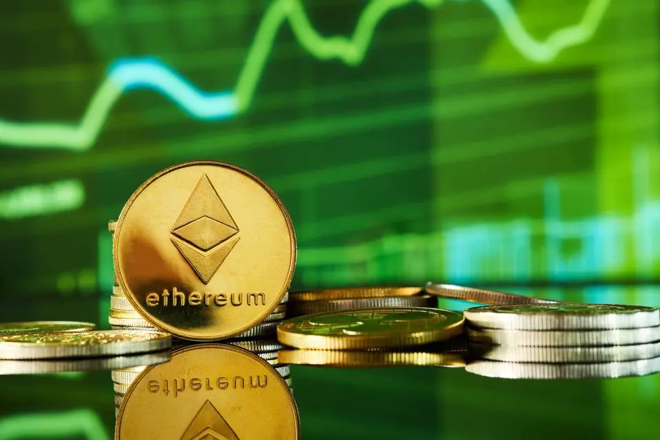 coin Ethereum xếp chồng lên nhau trên bề mặt phản chiếu với biểu đồ giao dịch ở phía sau